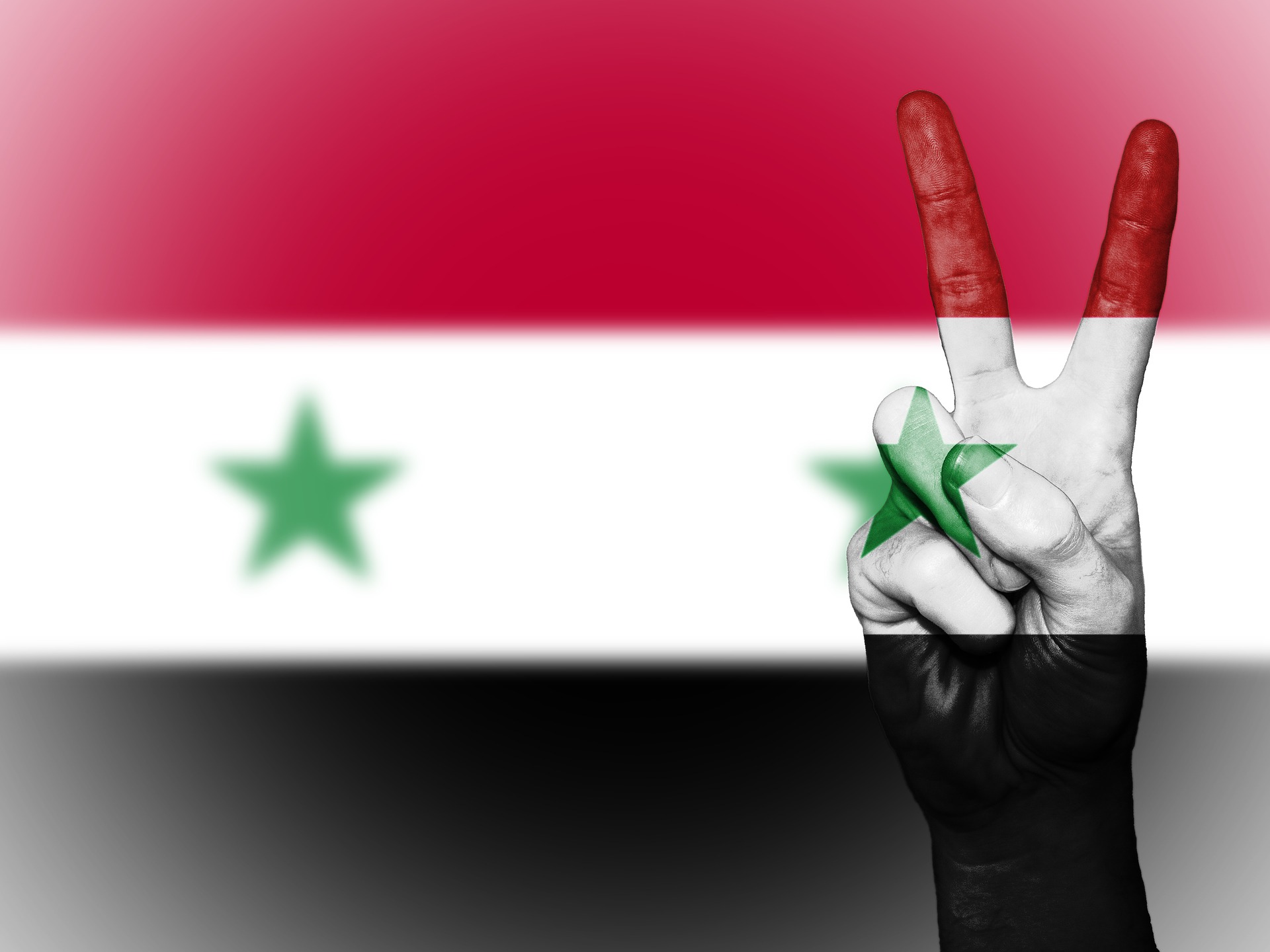 Syriens flagga med en hand som visar V-tecknet. 