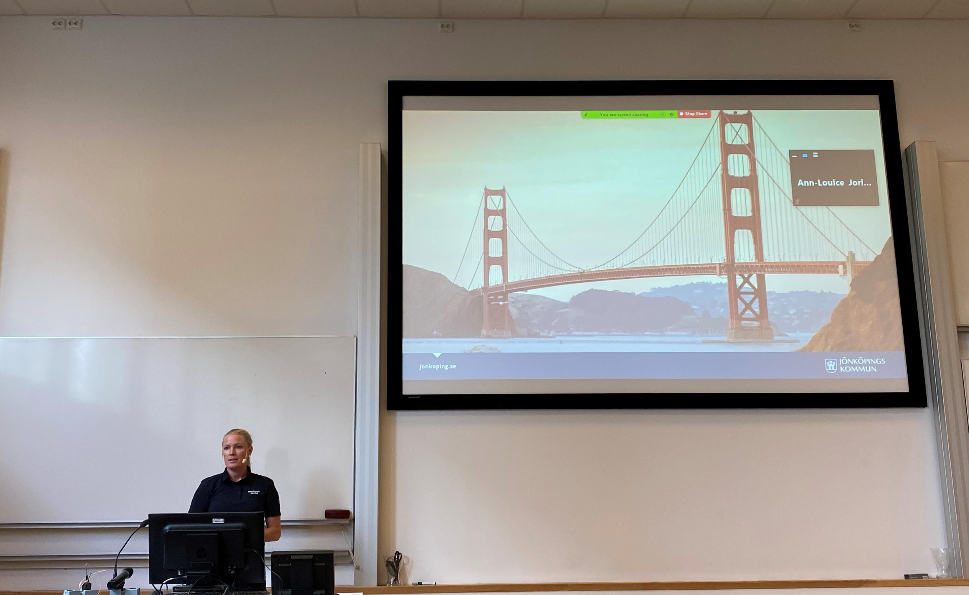 Elin Isfall, presenting and showing an image of the Golden Gate bridge in San Fransisco on the screen. 