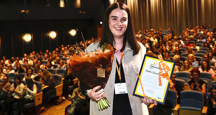 Malin Gummesson at the award ceremony with a diploma and flowers in her hands.
