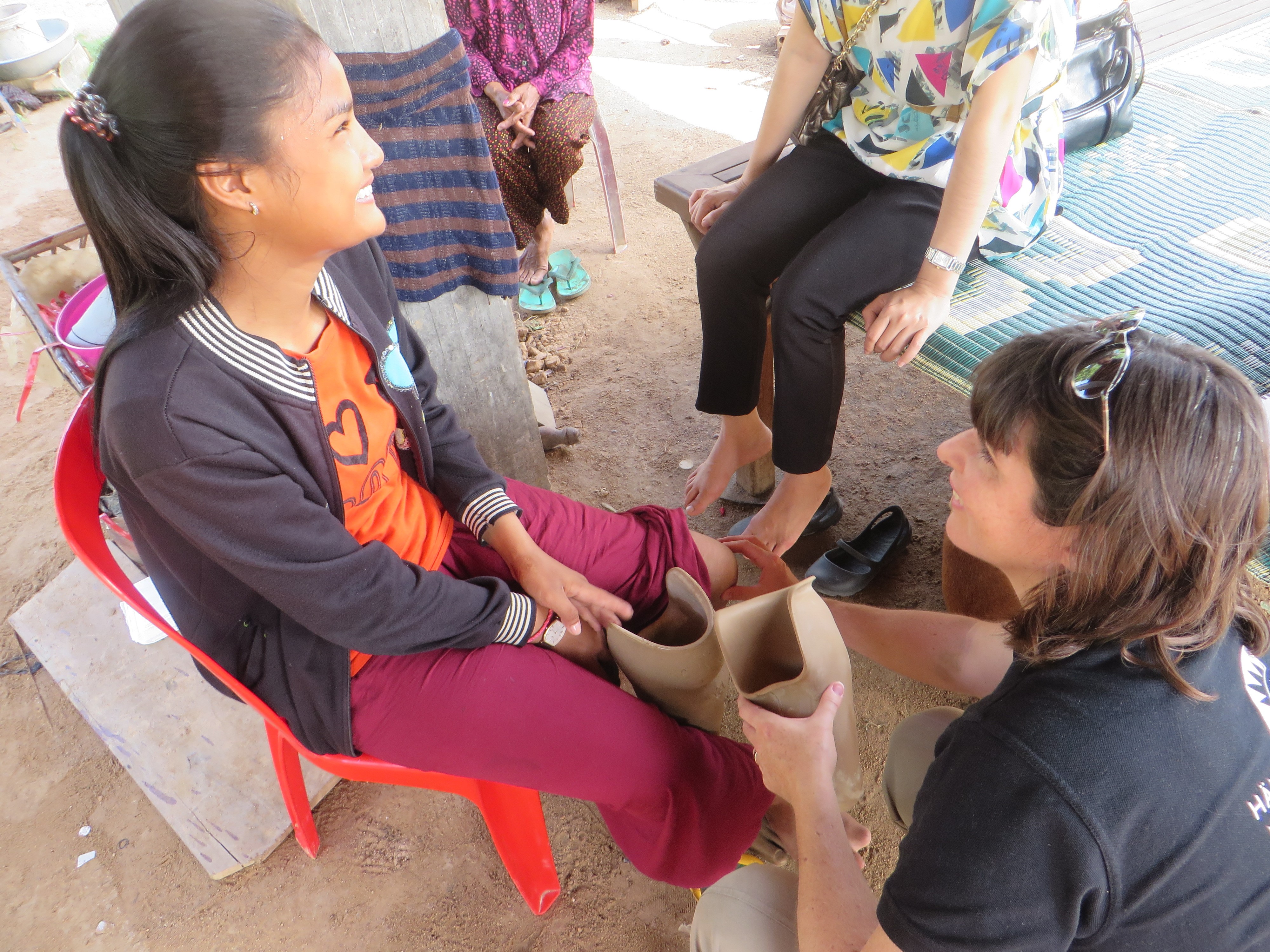 Professor Nerrolyn Ramstrand provar ut proteser på ung flicka i Kambodja. De är utomhus.