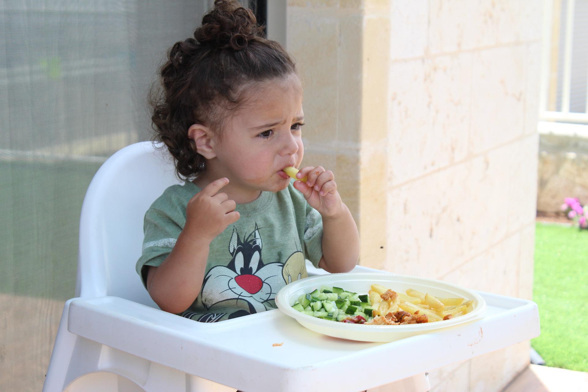 Litet barn i barnstol som äter