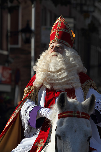 En person utklädd till Sinterklaas rider in i en stad